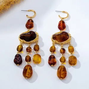 Boucles d'oreilles bohèmes ornées de pierres en résine ambrée irrégulière et de pendentifs dorés.