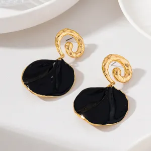 Boucles d'oreilles pendantes pétales or et noir avec une texture martelée élégante.