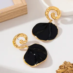 Boucles d'oreilles noires et dorées avec spirale texturée et charm pétale noir brillant.