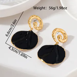 Vue détaillée de boucles d'oreilles pendantes pétales noir et or au design texturé spiralé.