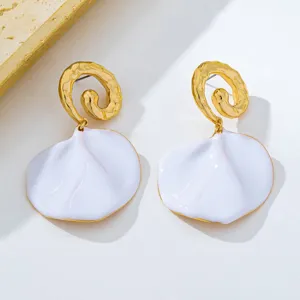 Boucles d'oreilles pendantes en métal doré spirale et pétales émaillés blancs détail.