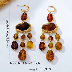 Boucles d'oreilles pendantes bohèmes en résine ambre avec franges en métal doré.