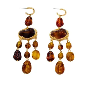 Boucles d'oreilles bohèmes en résine marron avec pampilles ambrées irrégulières.
