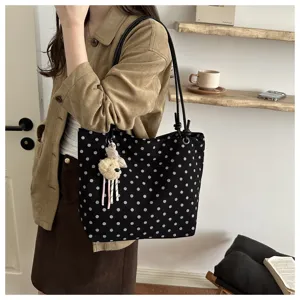 Vista dettagliata della borsa a tracolla in tela con pois alla moda per outfit autunnali.