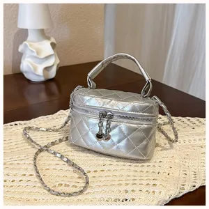 Silver quilted mini vanity bag detail, elegant chain strap and metal zipper decoration.