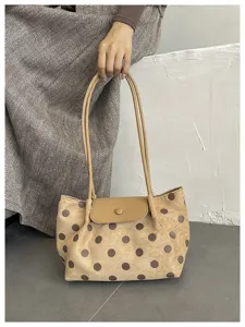 Dettaglio di una borsa a spalla chic in camoscio con pois marroni e doppi manici sottili.