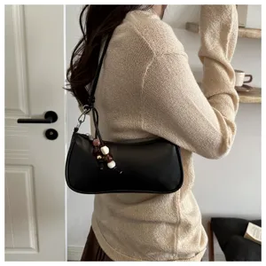 Black baguette shoulder bag detail featuring chic beaded pendant and minimalist casual style.
