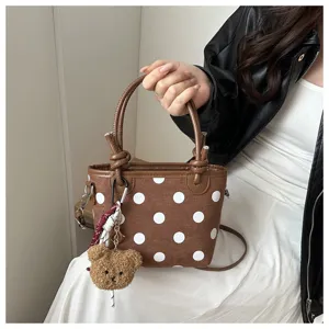 Vista ravvicinata dettagliata della borsa marrone a pois con simpatico ciondolo orsetto.