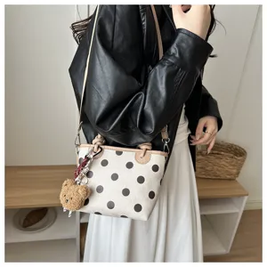 Primo piano della borsa a secchiello a pois di tendenza con grazioso ciondolo e tracolla.