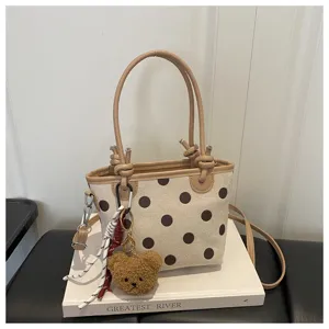 Borsa a secchiello in tela elegante con pois marroni, manici superiori e ciondolo orsetto peluche.
