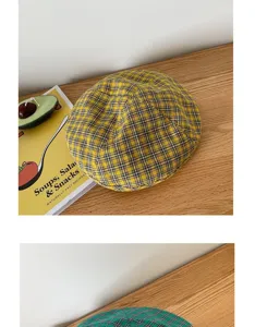 Vista detallada de una boina de cuadros amarilla sobre una mesa de madera con decoración.