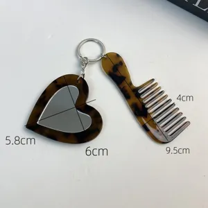 Detailed view of the chic acetate heart mirror and comb keychain, stylish bag accessory.