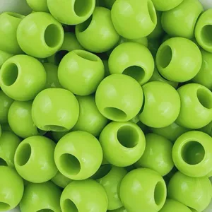 Dettaglio in primo piano di perle in acrilico verde chiaro con foro grande, superficie liscia lucida