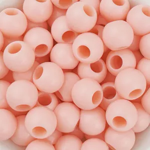 Primo piano dettagliato di perline tonde in acrilico rosa con foro grande, superficie liscia.