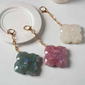 Close-up of cute four-leaf clover resin keychains with gold chain and lobster clasp.