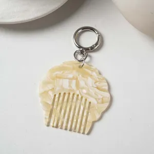 Close-up detail of portable mini acetate shell comb keychain with glossy marble texture.
