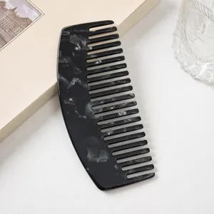 Black marbled acetate wide tooth comb for hair styling, elegant curved design detail view.