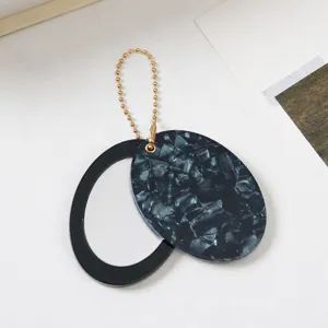 Ovaler kompakter Taschenspiegel Schlüsselanhänger mit Marmormuster und goldener Perlenkette.