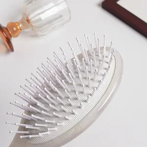 Detailed view of white air cushion hair comb with soft bristles, close-up texture shot.
