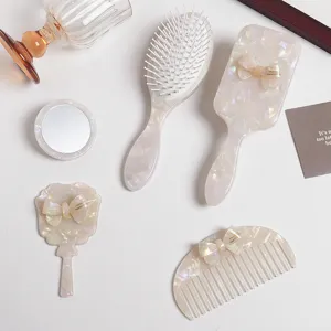 Detailed close-up shot of pearlescent acetate hair comb and vanity mirror set with bows.