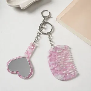 Detailed view of the pink marble acetate heart mirror and comb keychain pendant accessory.