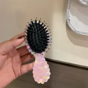 Vista dettagliata di una spazzola per capelli rosa marmorizzata con setole nere e manico.