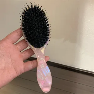Vista dettagliata della spazzola per capelli rosa marmorizzata con setole morbide e cuscino.