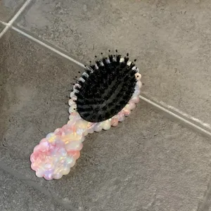 Pink acetate hair brush detail, portable air cushion massage comb with sleek glossy finish.