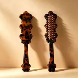 Tortoiseshell acetate hair brush with massage air cushion and unique wavy floral handle design.