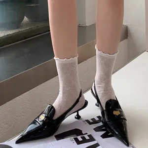 Black patent leather pointed slingback kitten heels paired with white lace ruffle socks.