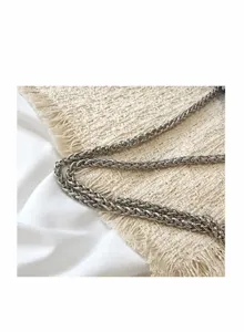 Women shoulder bag detail featuring metal chain strap and elegant tweed fabric design for evening.