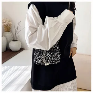 Detailed view of women's fashion sequin bucket bag with chic pearl chain strap for evening events.