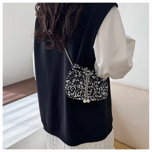 Black sequin bucket bag detail showing sparkling paillettes, pearl drawstring, and chain.