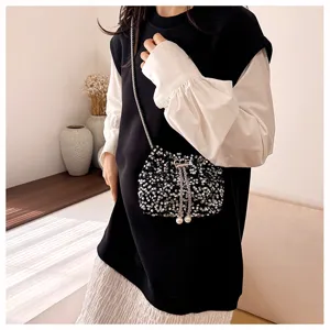Chic sequin bucket bag with metal chain and pearl details, perfect for evening wear.