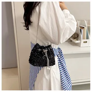 Close-up of black sequin bucket bag with metal chain strap and pearl charm details.