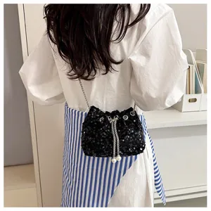 Detailed view of black sequin bucket bag with chic pearl pendant chain strap for women outfit.