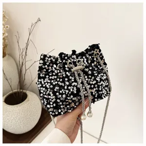 Detail shot of a fashionable black sequin bucket bag with metal chain and elegant pearl tassels.