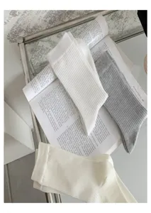 Vue détaillée de chaussettes mi-mollet côtelées pour femmes en blanc et gris, bord roulé en coton.