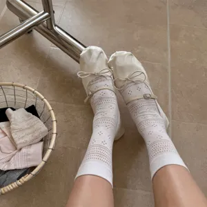 Detailaufnahme weißer Mesh-Hohlsocken kombiniert mit eleganten Satinstift-Ballerinas.