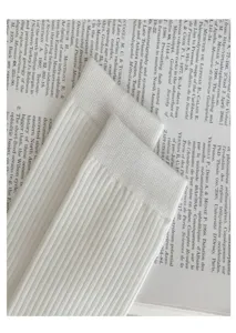 Gros plan détaillé de chaussettes montantes côtelées blanches en coton avec texture douce.