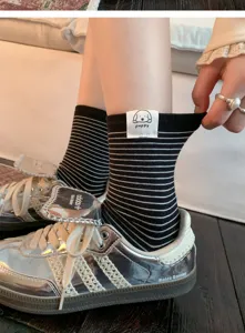 Close-up detail of women's black and white striped mid-calf cotton socks with cute puppy label