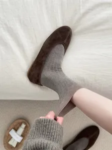 Detailed view of grey ribbed cotton mid-tube socks paired with brown suede flat shoes.