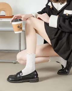 White lace ruffle socks with black Mary Jane shoes, stylish summer vintage daily footwear detail.