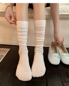 Detail view of white ribbed stack socks worn on legs with stylish ballet flat shoes.