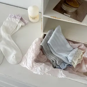 Detail view of women's soft cotton mid-tube socks with delicate ruffled lace trim design.