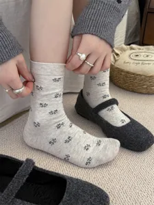 Close-up detail of vintage floral patterned mid-calf socks in grey, paired with casual shoes.