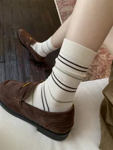 Close-up van dames retro gestreepte sokken met bruine loafers, gezellig lifestyle detail.