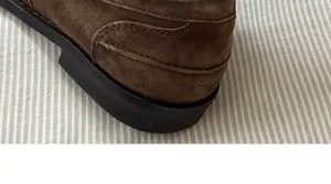Brown suede shoe heel detail close-up view showing fine texture and neat stitching work.