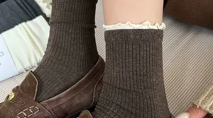 Close-up detail view of stylish brown ribbed mid-calf socks featuring white lettuce trim.