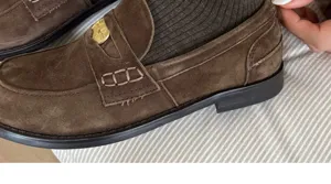 Close-up detail of brown suede loafers paired with ribbed dark socks, retro style shoe view.